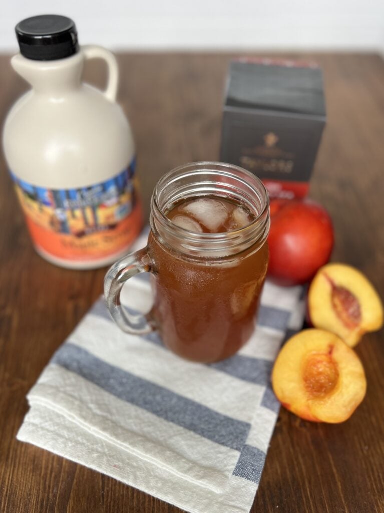 Maple nectarine tea in a glass jar surrounded by the ingredients required for the recipe
